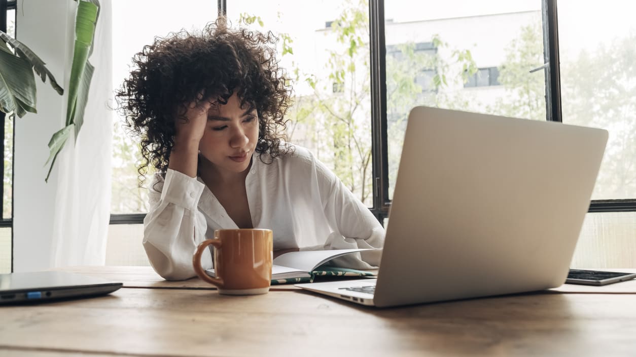 A woman sitting at a desk with a laptop and a cup of coffee.