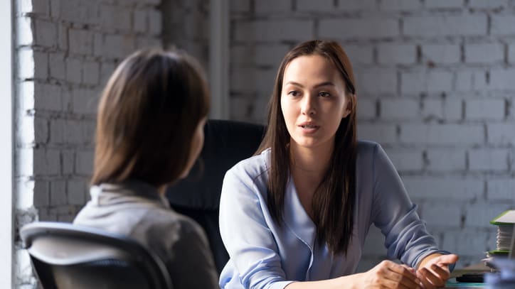 A woman is talking to another woman in an office.