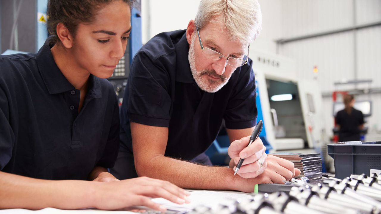 A man and woman working on a machine in a factory.