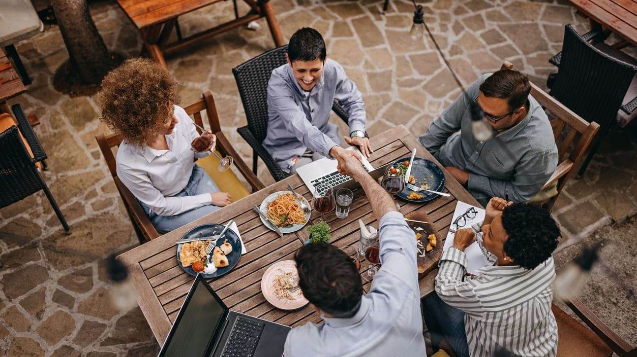 A group of people sitting around a table at an outdoor restaurant.