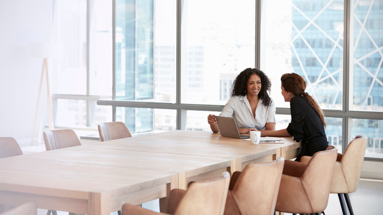 Two women sitting at a table in a conference room.