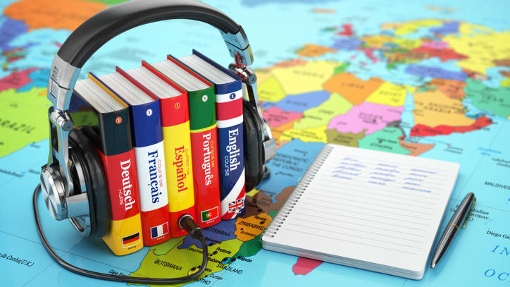 A book with headphones and a notebook on top of a world map.