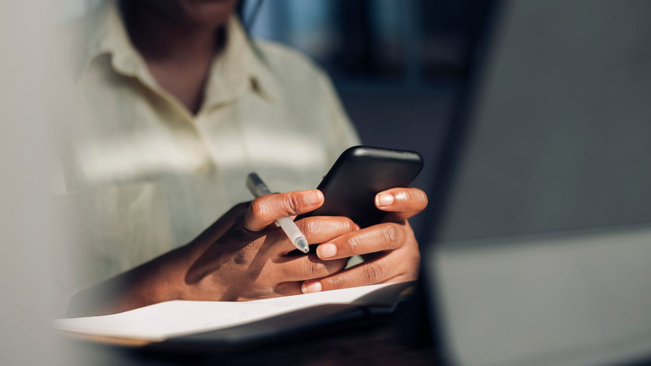 A woman using a cell phone while sitting at a desk.