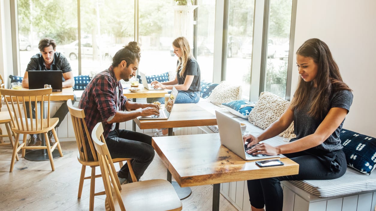 A group of people working on laptops in a cafe.