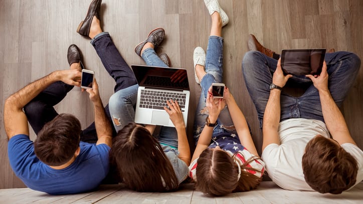 A group of people sitting on the floor with laptops.