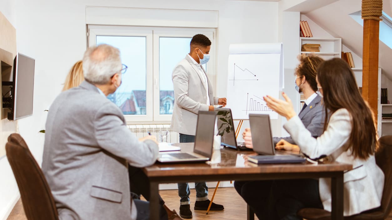 A group of business people sitting around a table in a meeting room.