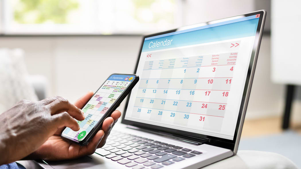 A man is using a laptop with a calendar on it.