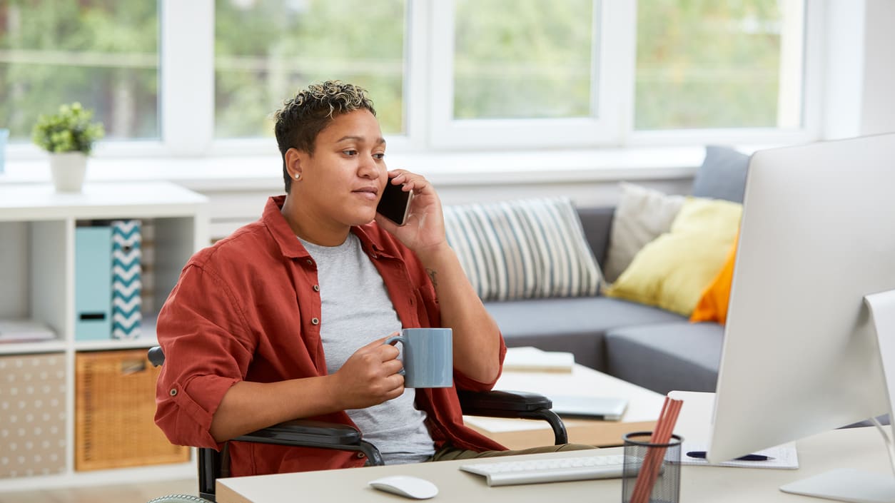 A person in a wheelchair talking on the phone at home.