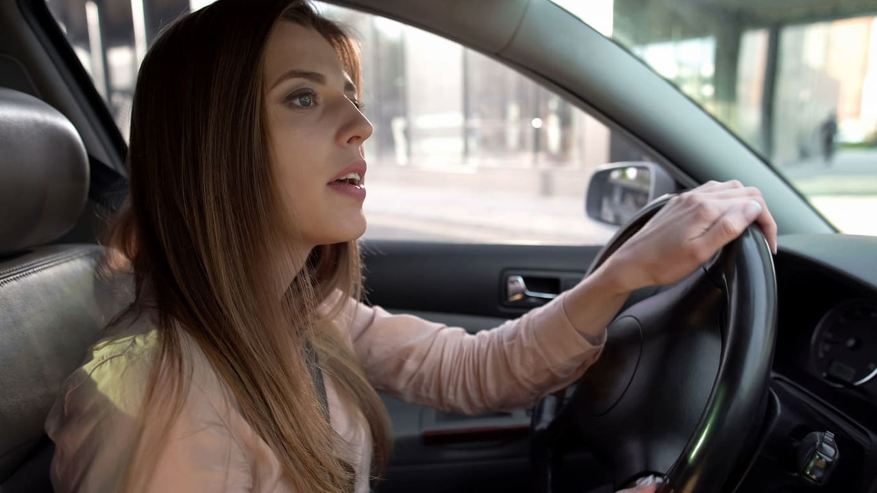 A woman driving a car with her hands on the steering wheel.