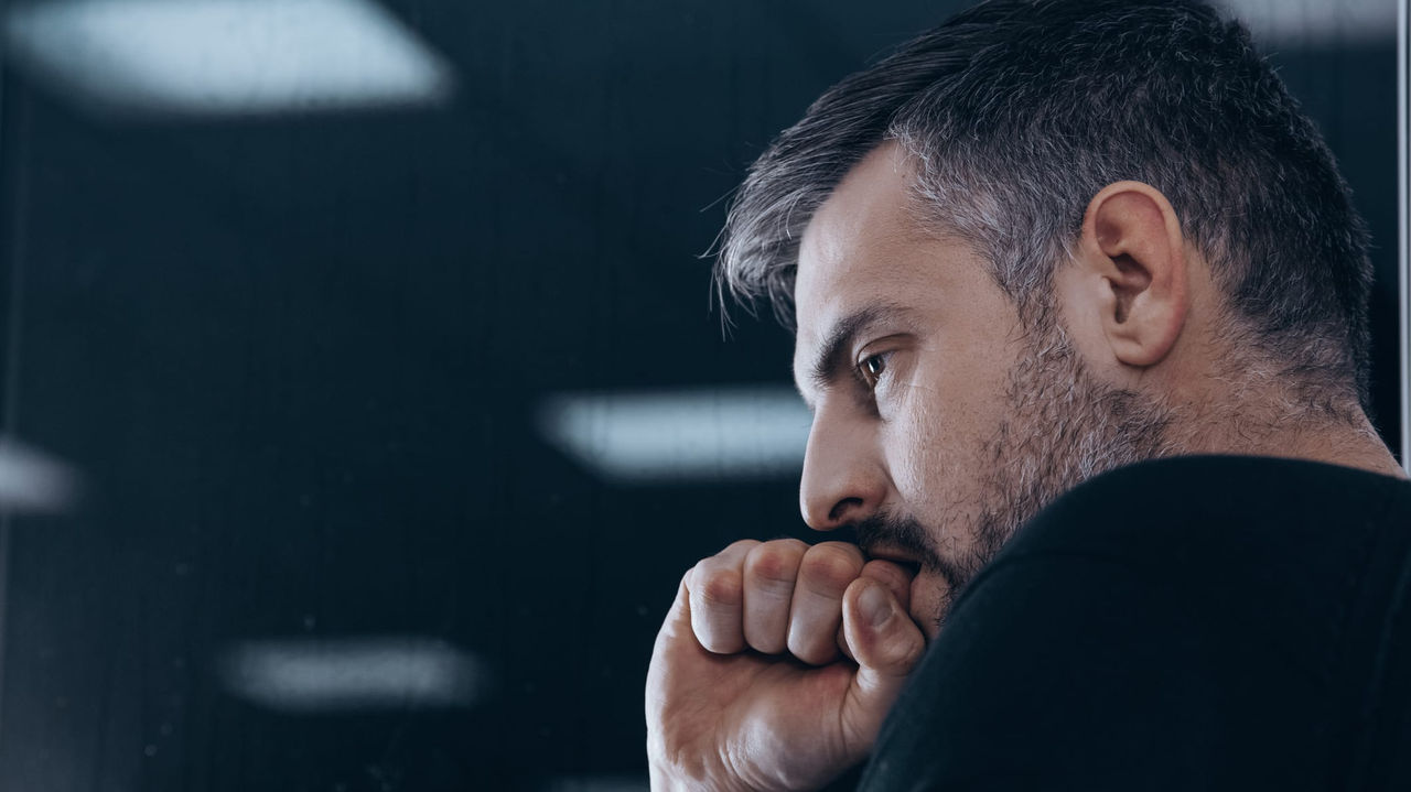 A man with a beard looking out of a window.