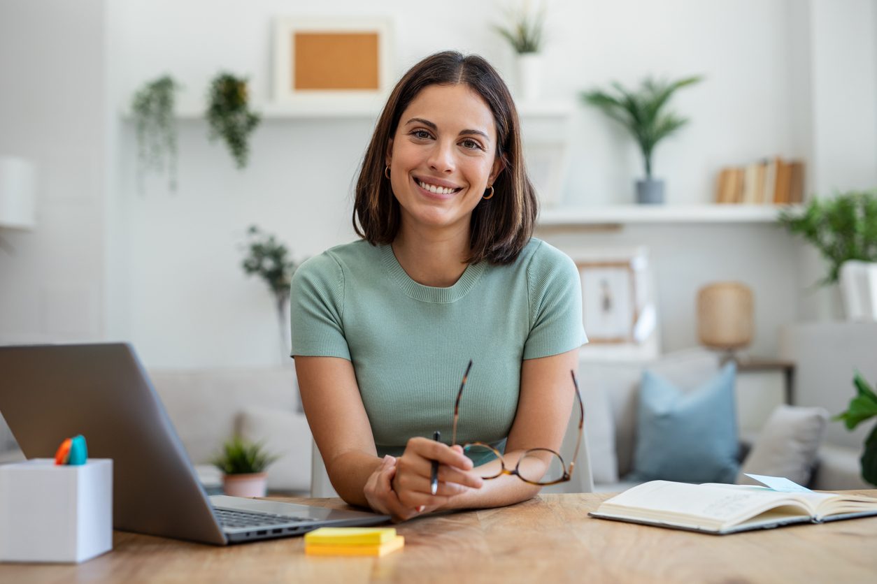 A young professional sits at her desk with a cheerful expression.