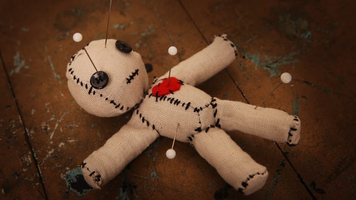 A stuffed doll with pins on it.
