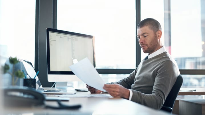 A man sitting at a desk reading a document.