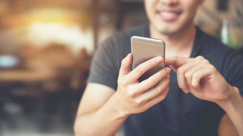 A man is looking at his phone while sitting at a table.