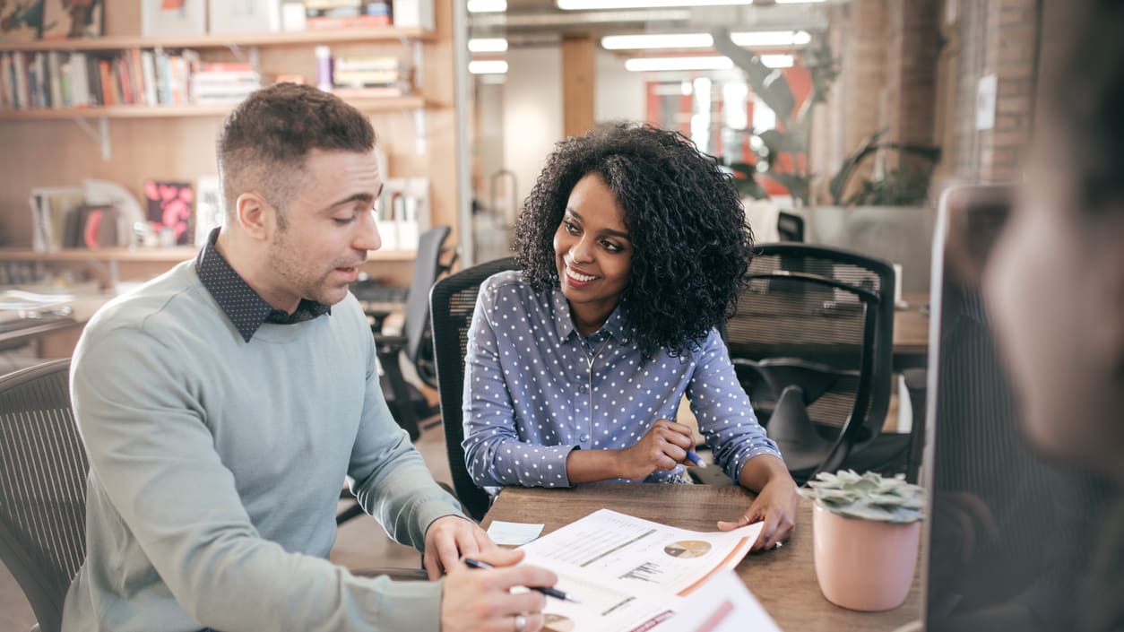 Two people sitting at a table in an office.