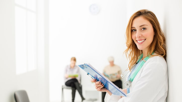 A female doctor holding a clipboard in a waiting room.