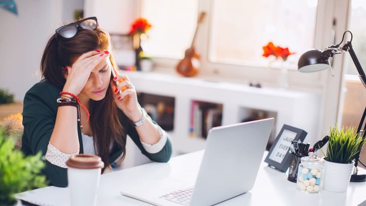 A woman is sitting at a desk with a laptop.