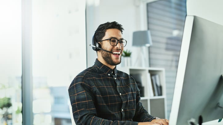 A man wearing a headset is working on a computer.