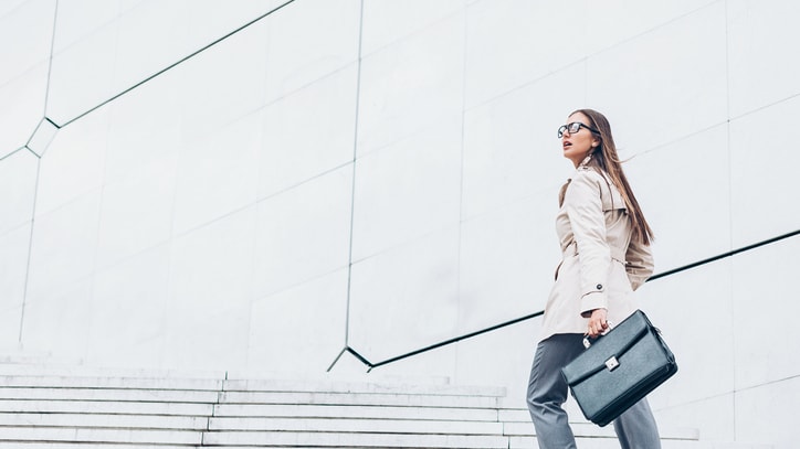 A business woman is walking down stairs with a briefcase.