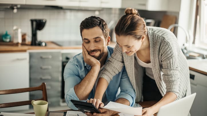 A couple looking at their finances on a laptop in the kitchen.