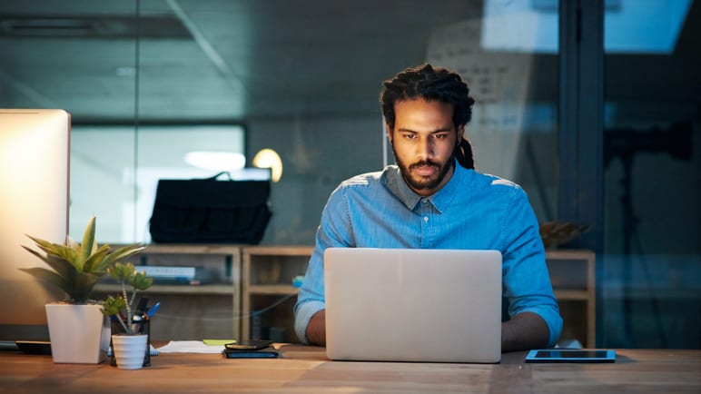 A man working on a laptop in an office.