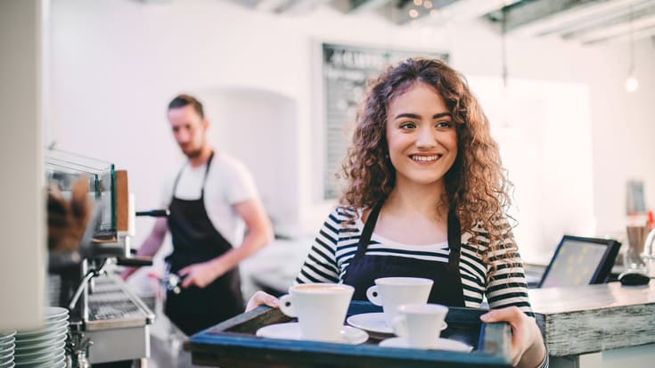 A woman holding a tray in a coffee shop.