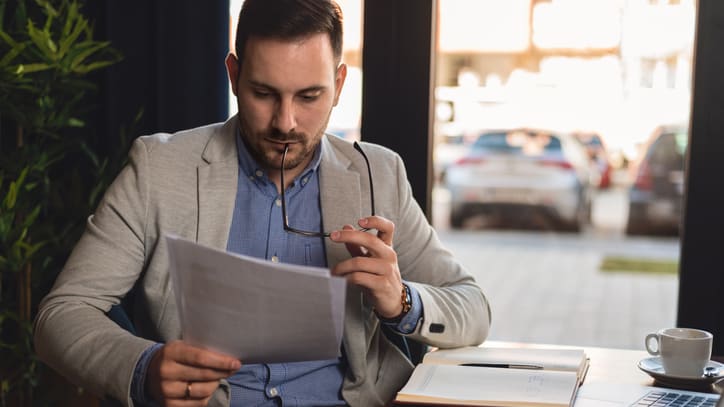 A man sitting at a table looking at a piece of paper.