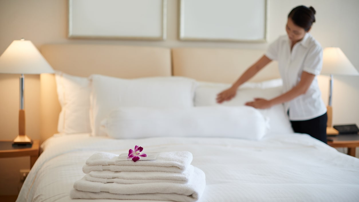 A woman is making a bed in a hotel room.