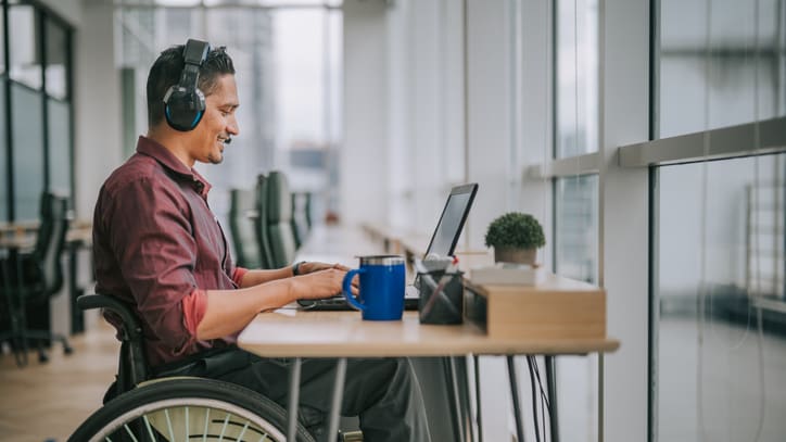 A man in a wheelchair working on a laptop.