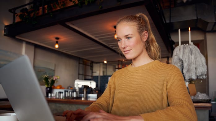 A woman working on a laptop in a coffee shop.