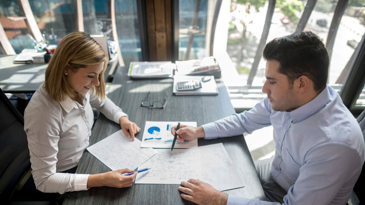 A man and woman sitting at a desk in an office.