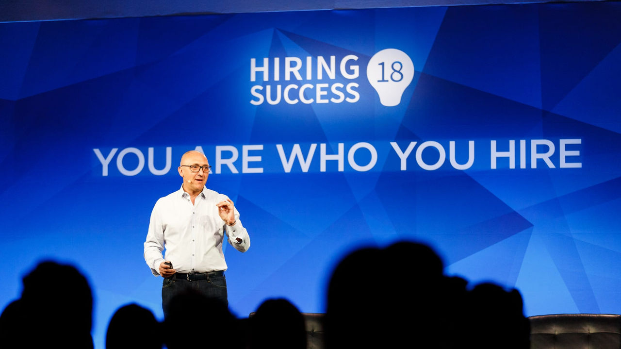 A man speaking on stage at a smartrecruits event.