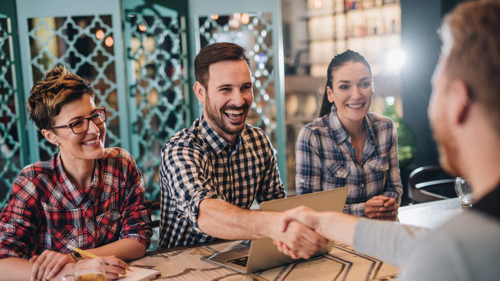 A group of people shaking hands at a table in a restaurant.