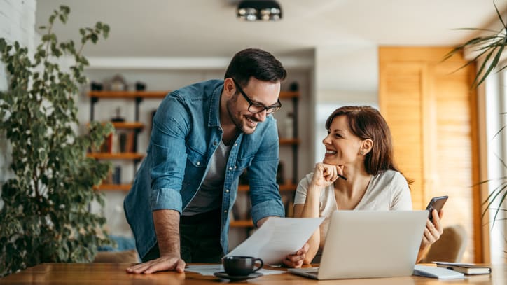 A man and woman are sitting at a table and looking at a laptop.