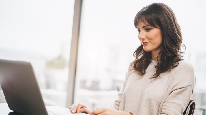 A woman sitting at a desk using a laptop.