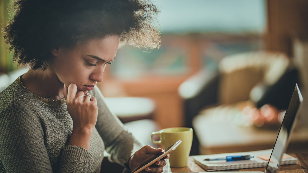 A woman looking at her phone while sitting at a table.