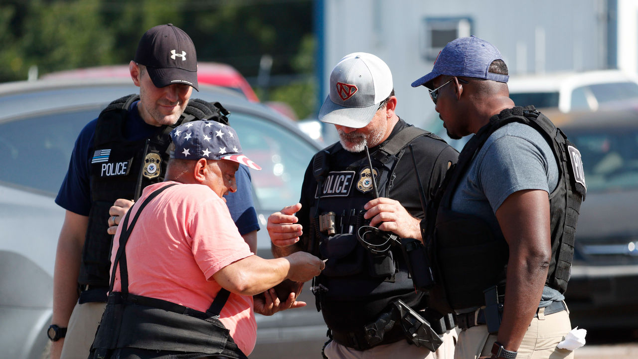 A group of police officers talking to each other in a parking lot.