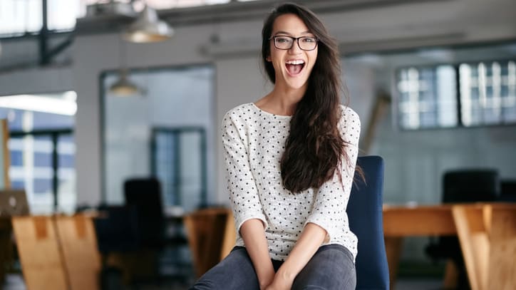 A young woman sitting on a chair in an office.