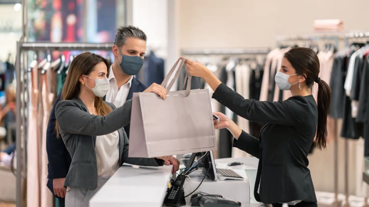 Two women wearing face masks at a clothing store.