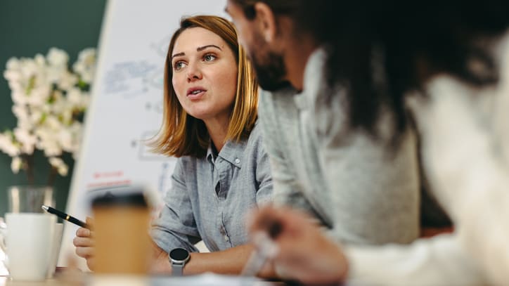 A group of people sitting around a table in a meeting.