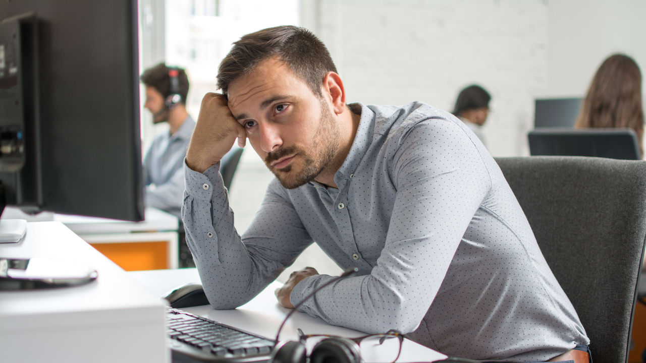 A man sitting in front of a computer with headphones on.