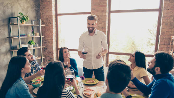 A group of people sitting around a table and drinking wine.