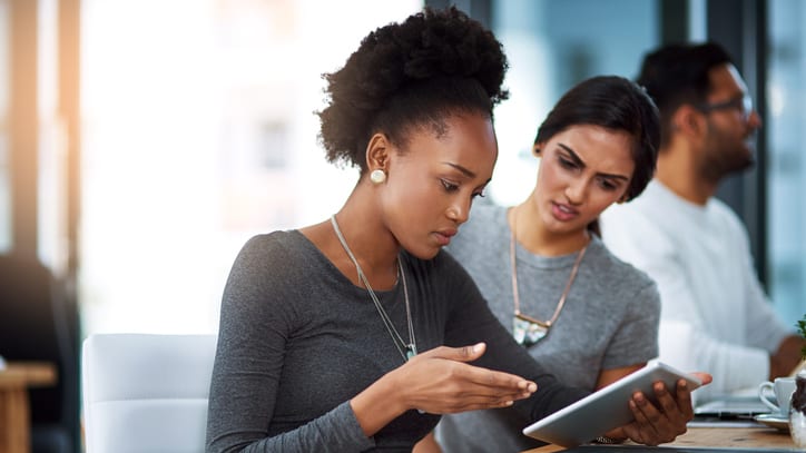 Two women looking at a tablet in an office.