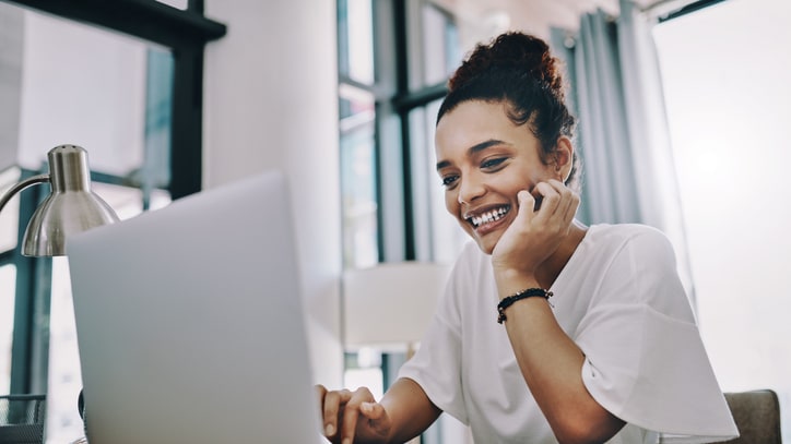 A woman is talking on the phone while working on her laptop.