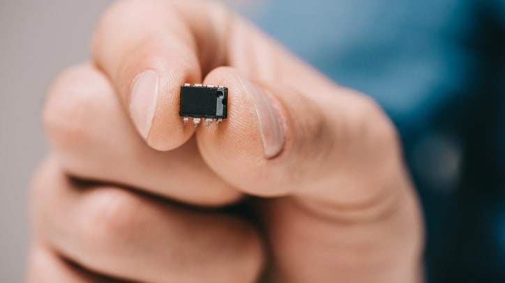 A person holding a small black chip in their hand.