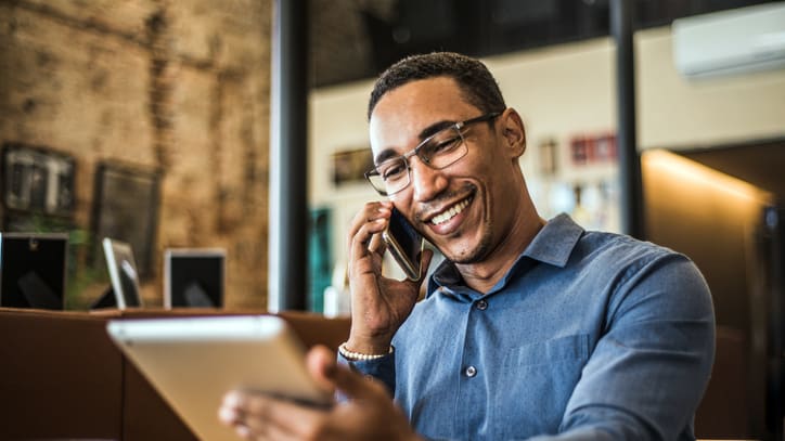 A man using a cell phone while sitting at a table in a coffee shop.