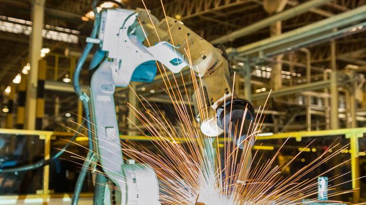 A robot is welding a piece of metal in a factory.