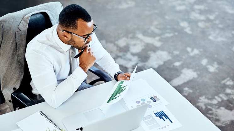 A businessman sitting at a desk looking at a laptop.