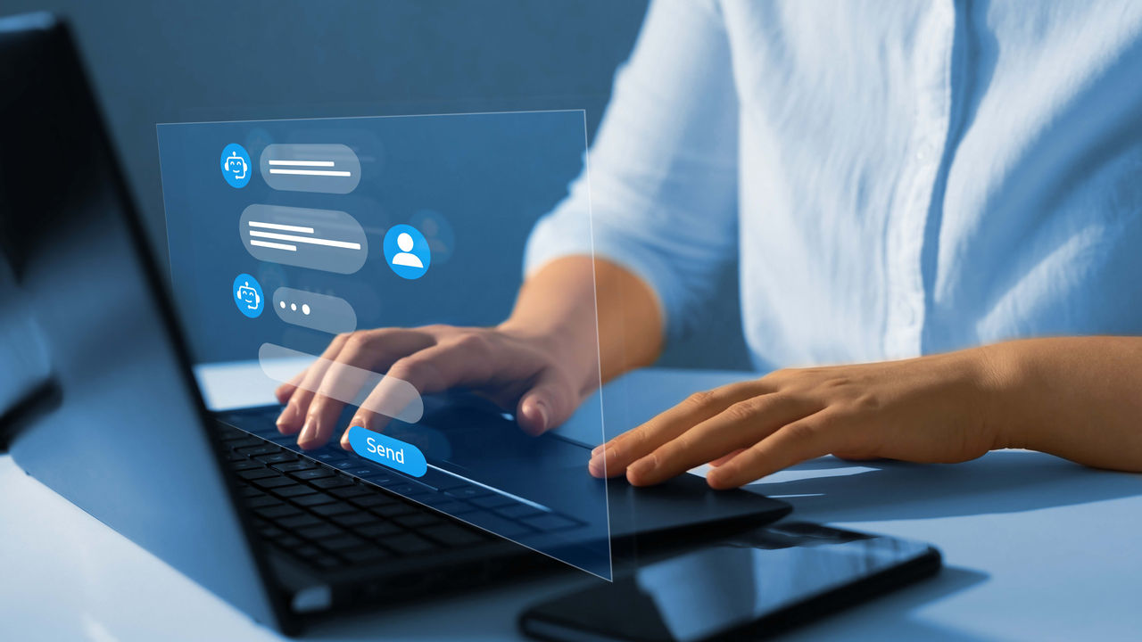 A woman is using a laptop with social media icons on it.