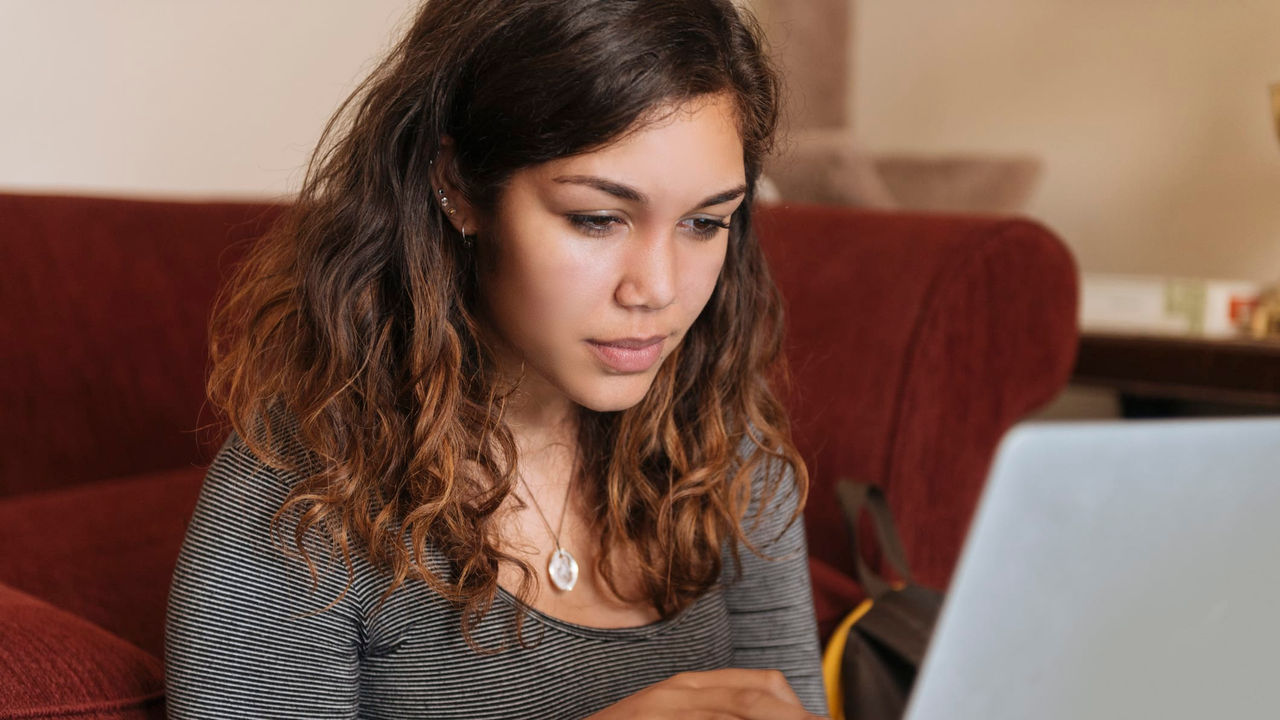 A young woman sitting on a couch using a laptop.